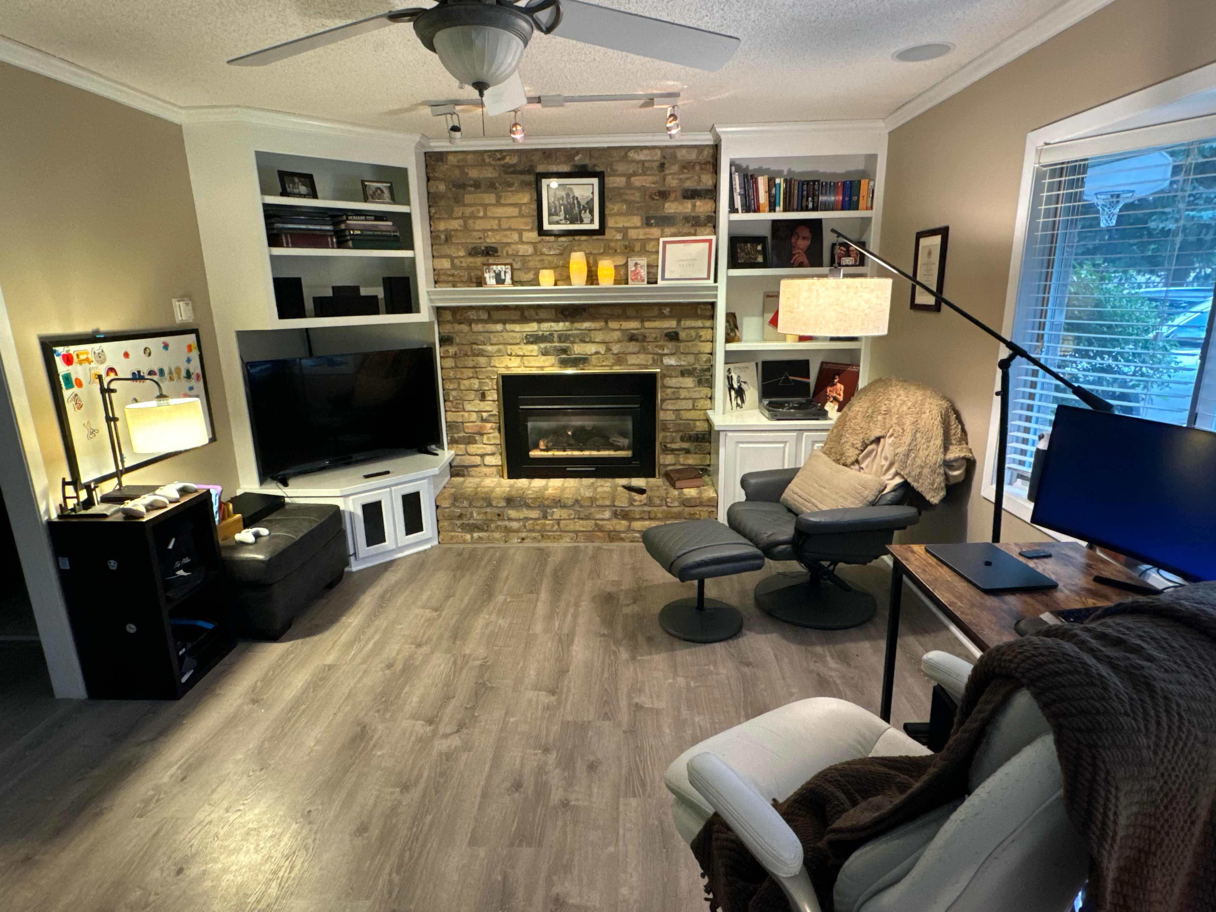 Living room with LVP flooring, custom white built-ins and stone fireplace
